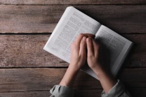 Religion.,Christian,Woman,Praying,Over,Bible,At,Wooden,Table,,Top