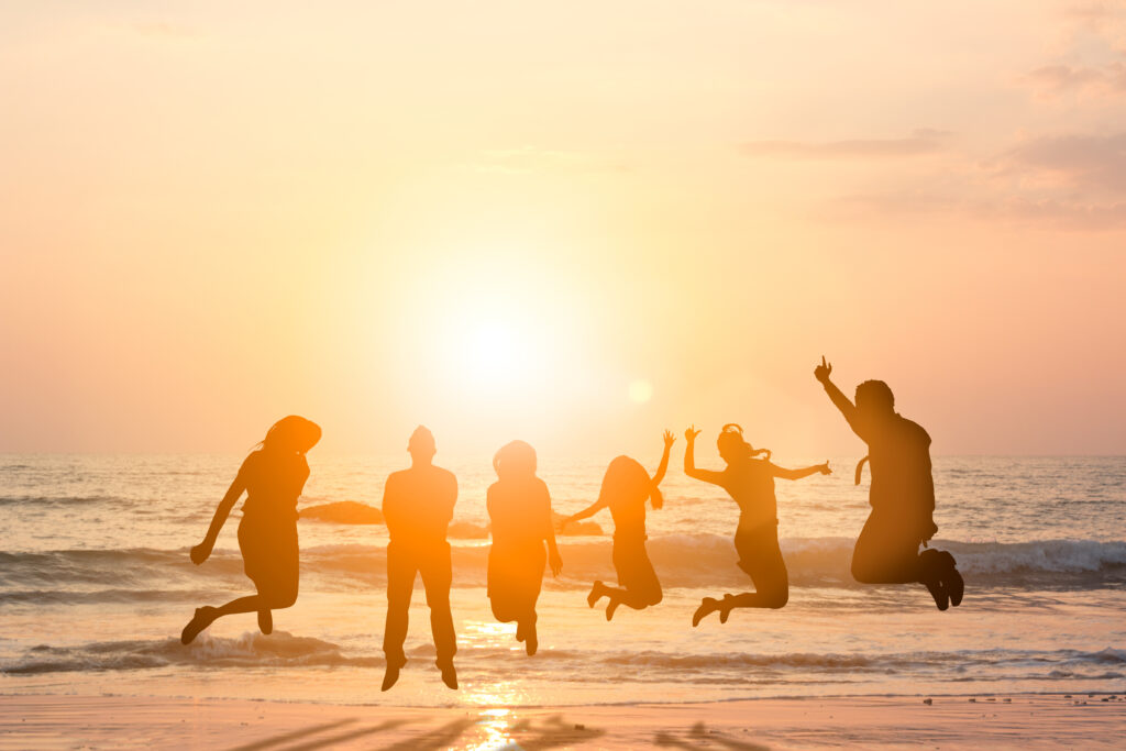 Silhouette,Friends,Jumping,With,Joy,And,Happiness,Over,Blurred,,Sand