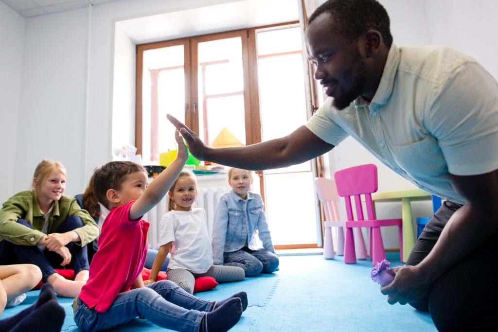 African,School,Teacher,Sitting,On,The,Floor,With,Children,In